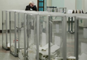 An observer waits for the start of ballot counting at a polling station after voting day in Kiev